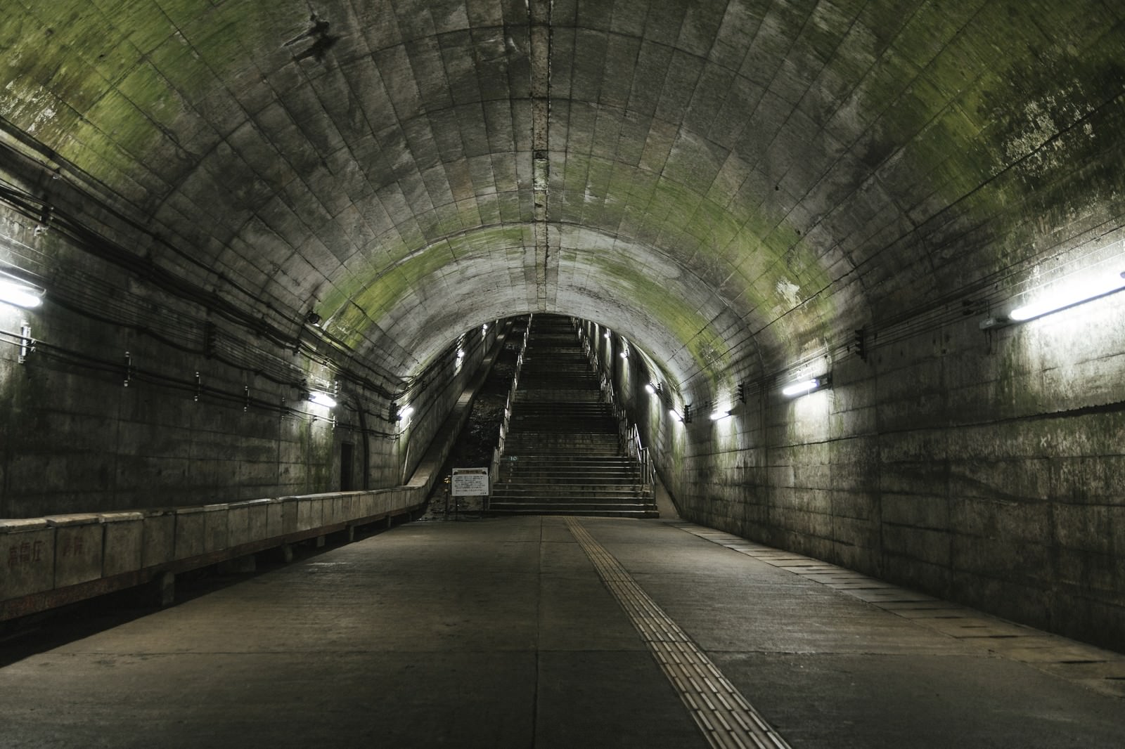 薄暗い照明の土合駅地下通路、奥に階段が見えるトンネル
