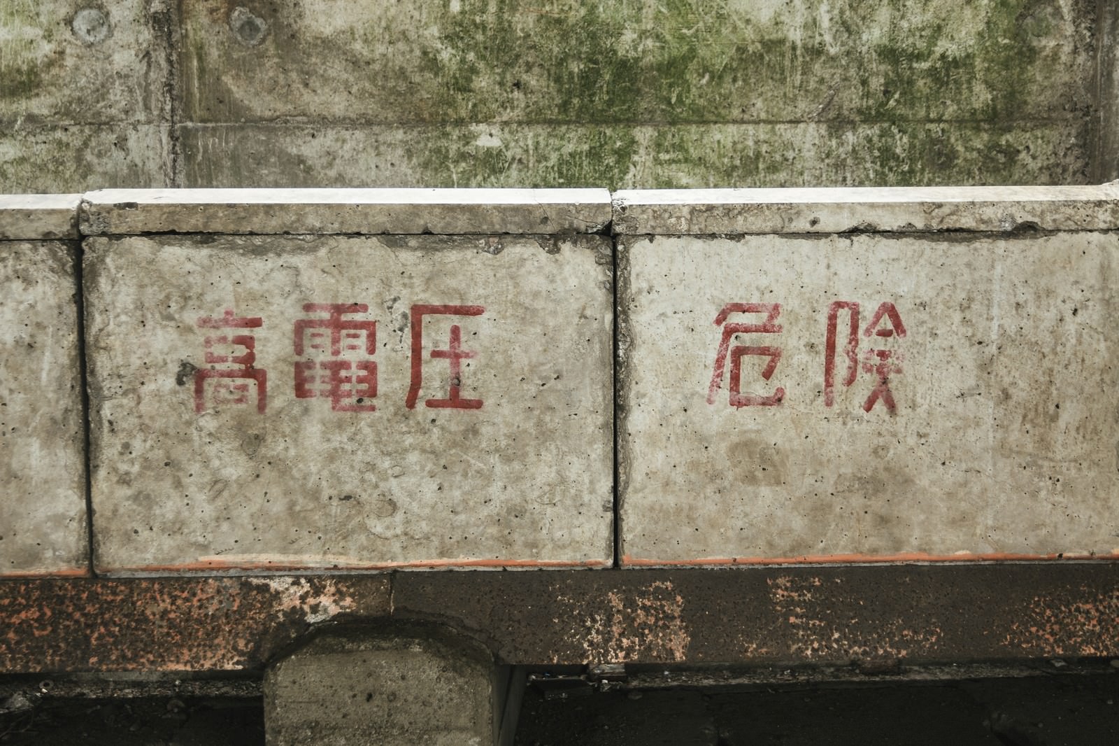 古いコンクリート壁に赤い文字で書かれた高電圧危険の注意書き