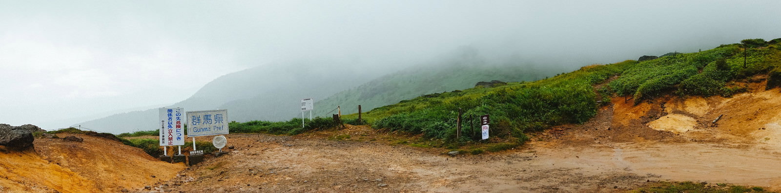 霧に包まれた毛無峠の立入禁止看板とパノラマ風景