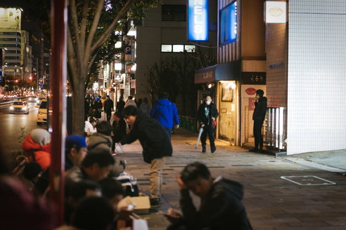徹夜で並ぶ歩道の長蛇の行列と待つ人々の群れ