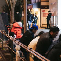 夜間の歩道に徹夜で作られた長蛇の列と大勢の群衆の写真