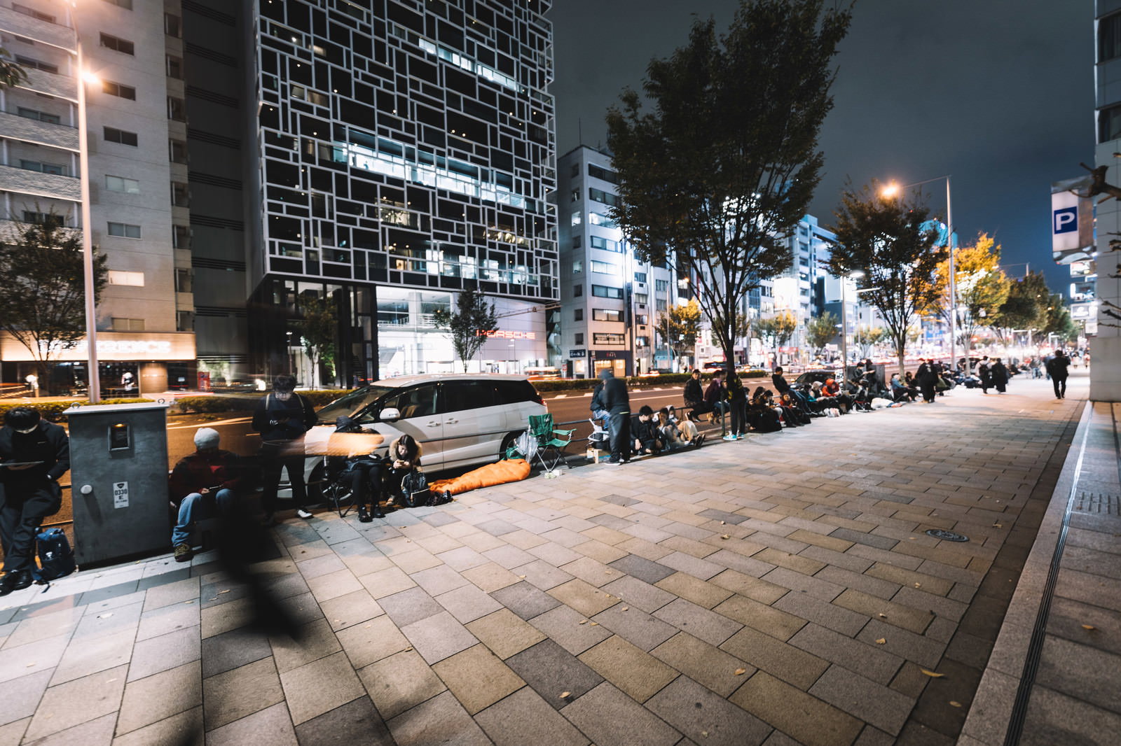 夜の街で歩道に長蛇の列を作る人々