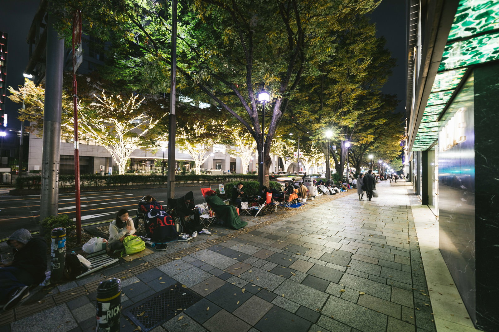 夜の歩道で徹夜行列に並ぶ人々