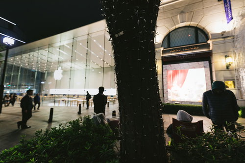 夜間のアップルストア表参道店舗前に並ぶ行列と人々