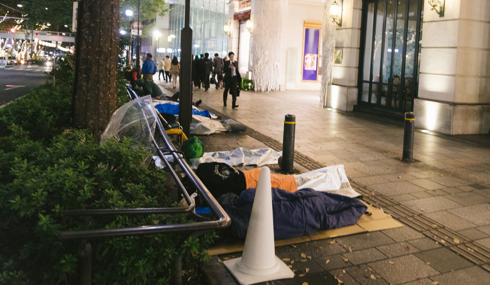 店舗前の歩道に寝袋を敷いて並ぶ人たちの徹夜行列の様子