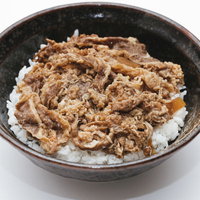茶色い丼に盛られた牛丼一人前、牛肉と玉ねぎがたっぷり乗った和食の写真