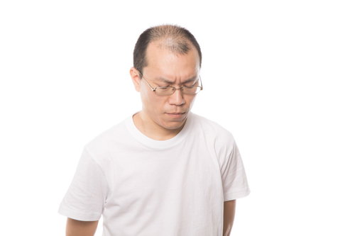 薄毛を気にして悩み苦しむ男性の頭頂部とうつむく表情