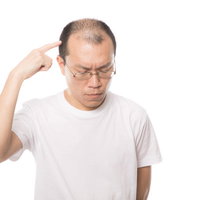 考えごとをしている薄毛の中年男性が頭を抱えるの写真