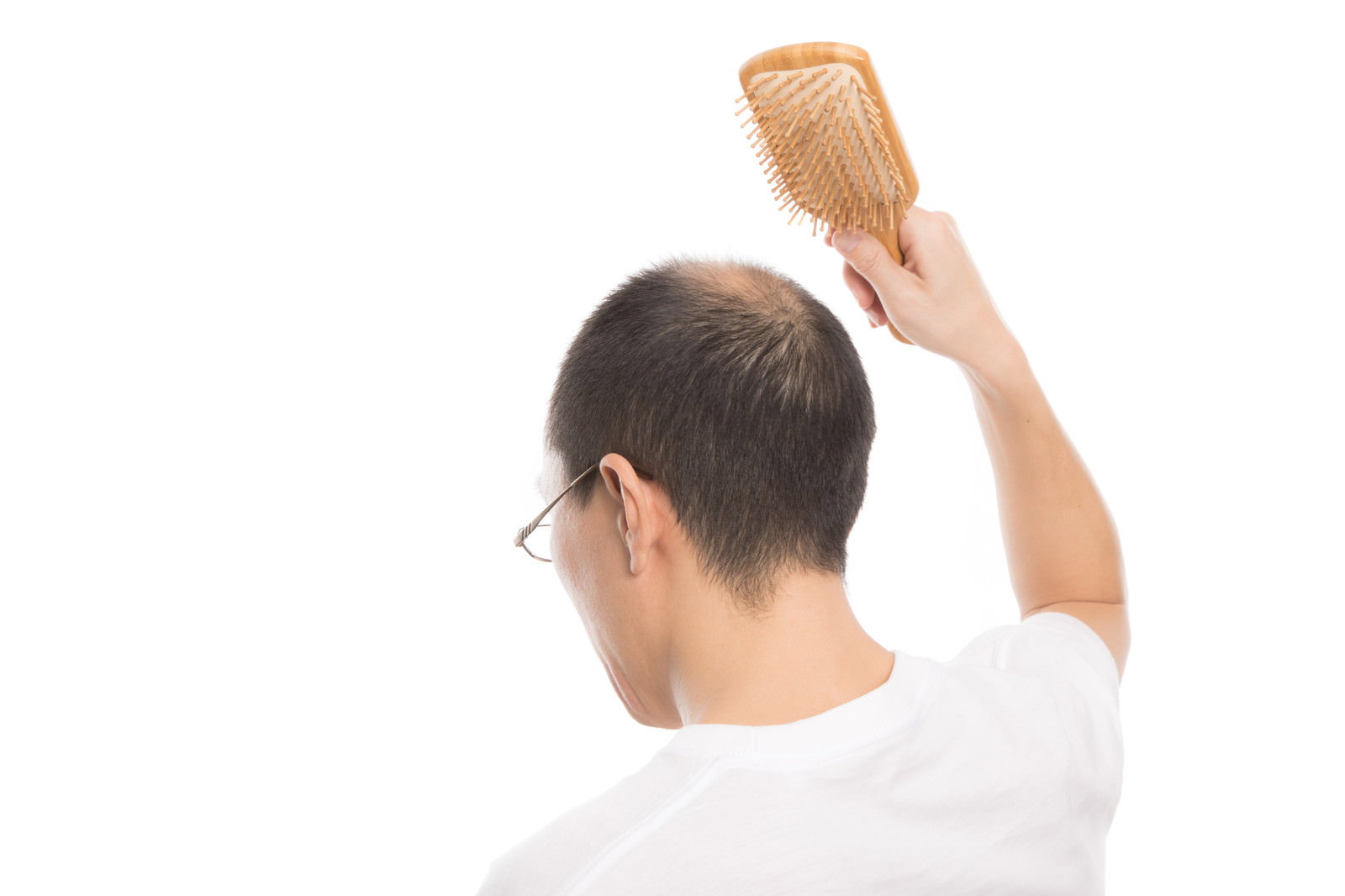 木製ブラシで頭皮マッサージをする薄毛の男性の後ろ姿［モデル：サンライズ鈴木］