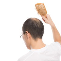 育毛促進！木製ブラシで頭皮マッサージをする薄毛男性の写真