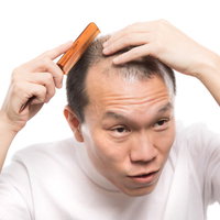 薄毛やAGA、ハゲを気にして櫛を持つ男性の写真