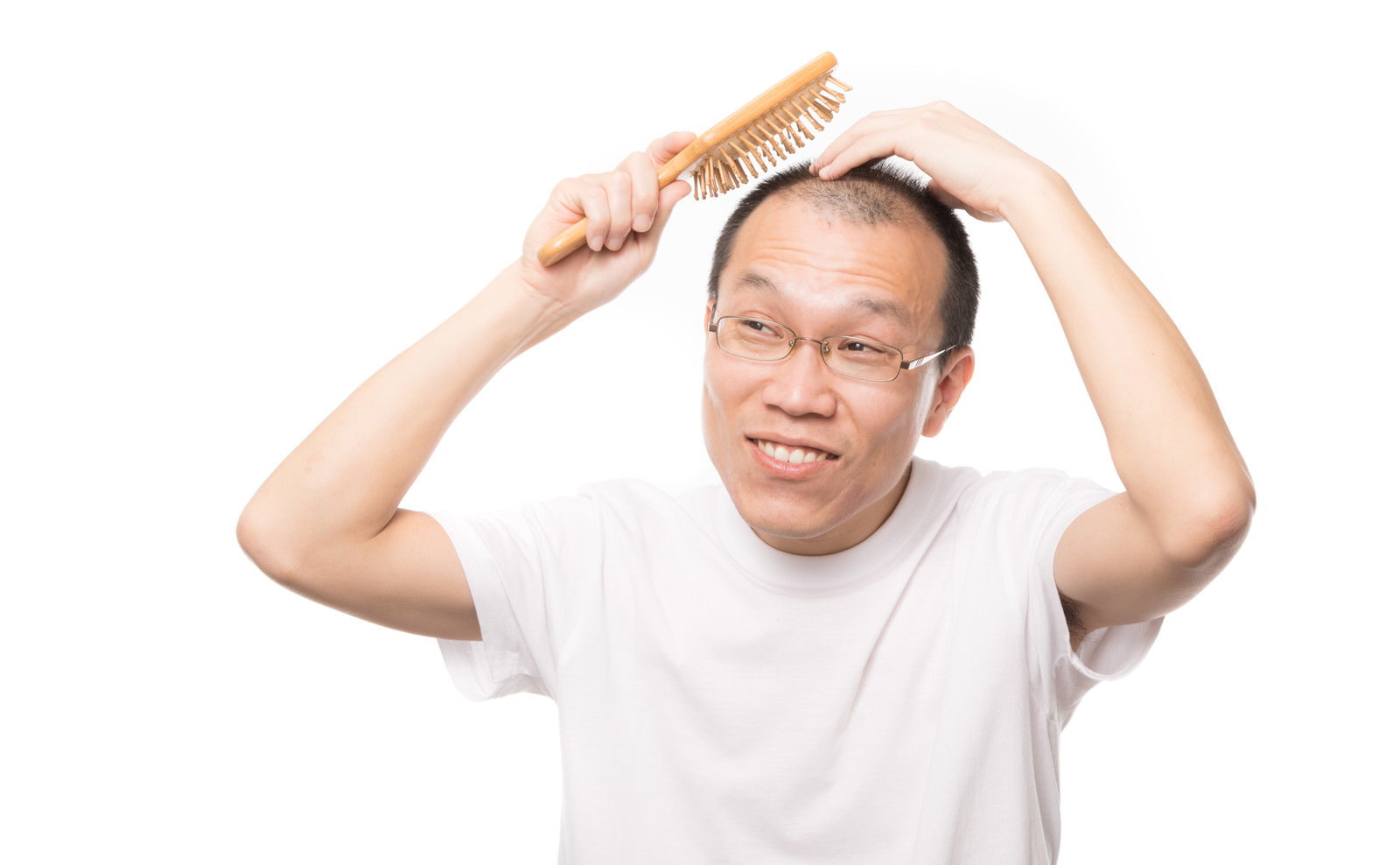 木製ブラシを両手で持ち、頭頂部をたたく眼鏡をかけた薄毛の男性［モデル：サンライズ鈴木］