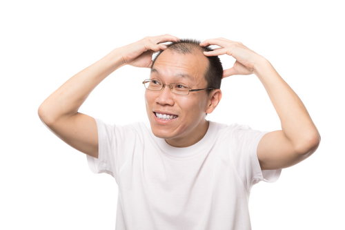 笑顔で頭皮マッサージする男性が鏡で薄毛を確認