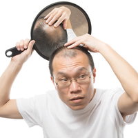 手鏡で頭頂部をヘアチェックする薄毛男性の抜け毛対策の写真