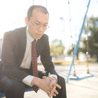 公園のベンチで頭を抱えて悩むハゲリーマンの写真