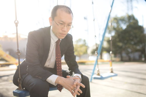 公園のベンチで頭を抱えて悩むハゲリーマン