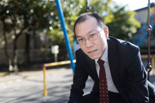 公園で部下の愚痴を聞く薄毛の部長が疲れた表情でブランコに座る