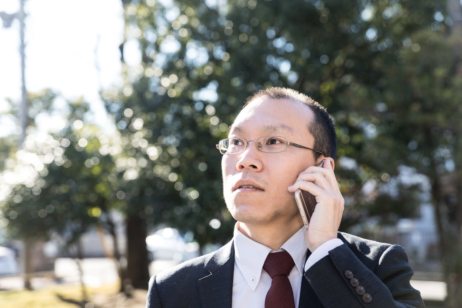 スマートフォンで電話をしながら驚いた表情をするスーツ姿の男性［モデル：サンライズ鈴木］