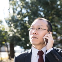 重要な約束を忘れていた時のスマホ通話中の男性の表情の写真