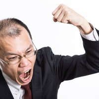 怒鳴り散らしてこぶしを振り上げるハゲリーマンの写真