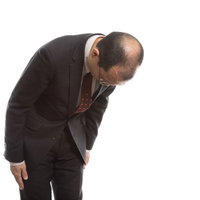 お辞儀で禿げた頭頂部を見せるサラリーマンの写真