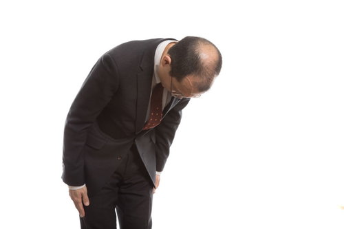 お辞儀で禿げた頭頂部を見せるサラリーマン