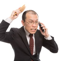 頭をかきながら困惑する男性の写真