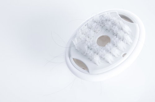 抜け毛が絡みついた白いシャンプーブラシ、ヘアケア用品