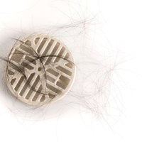 浴槽の白い排水口に溜まった抜け毛と脱毛の悩みの写真