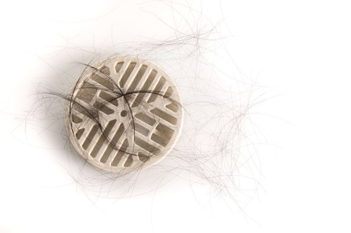 浴槽の白い排水口に溜まった抜け毛と脱毛の悩み