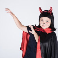 赤い角とマントのチビデビルが魔法を詠唱する仮装姿の写真