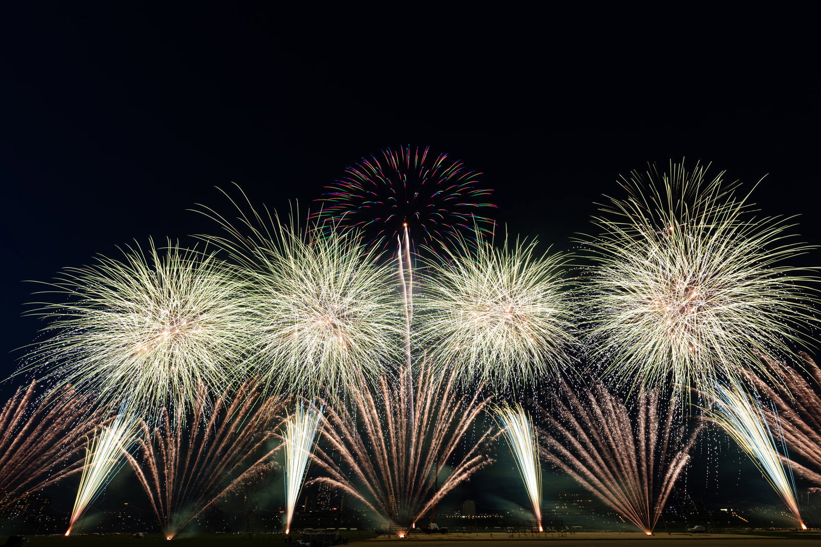 夜空に複数の色とりどりの打上花火が開花している様子