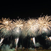 速射連発花火・スターマインが夜空に華やかに開花する光景の写真