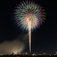 風が吹いて少しだけ光跡が流れる打上花火の夜空の写真