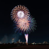 目の前に打ち上がる赤やオレンジ、緑色の花火の写真