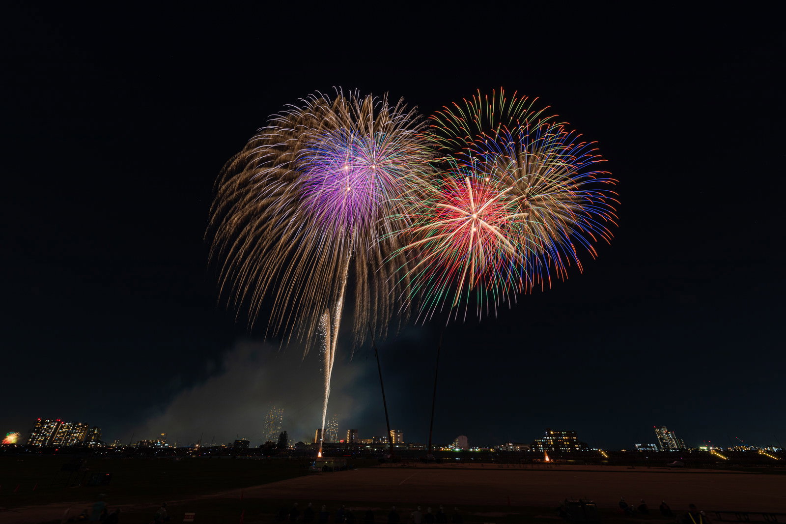 夜空に打ち上がる色とりどりの花火と河川敷の風景