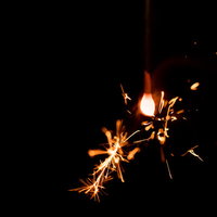 夜空に飛び散る線香花火の光跡と火の粉の軌跡の写真