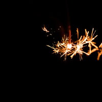 線香花火の火花が散る光跡：夏の夜を彩る儚い火の粒の写真