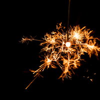 暗闇で弾ける線香花火のパチパチとした光跡の写真