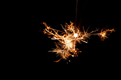 夜の暗がりで弾ける線香花火の金色の光跡と火の粉