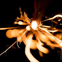 暗闇に描くせんこう花火の光跡と火の粉の放射状の広がりの写真