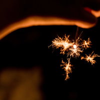 夏の終わりに儚く光る線香花火、暗闇で舞うオレンジ色の火花の写真