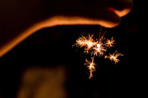 夏の終わりに儚く光る線香花火、暗闇で舞うオレンジ色の火花