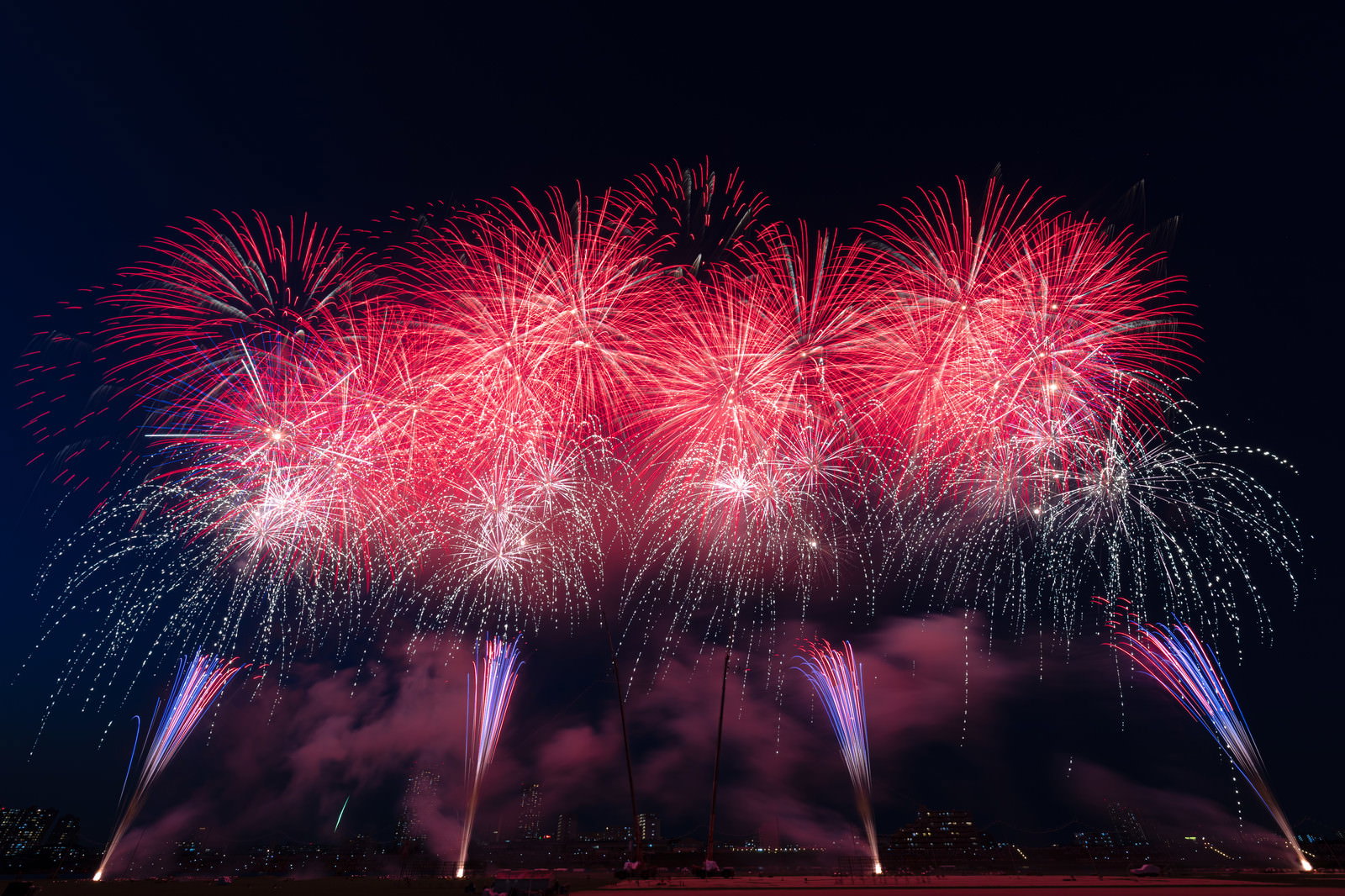 夜空に赤い花火が連続して打ち上がるスターマインの光景