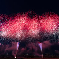 夜空に赤く咲く連続スターマインの打上花火の写真