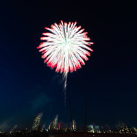 スーパークの夜空にぼやけて光る打上花火の光景の写真