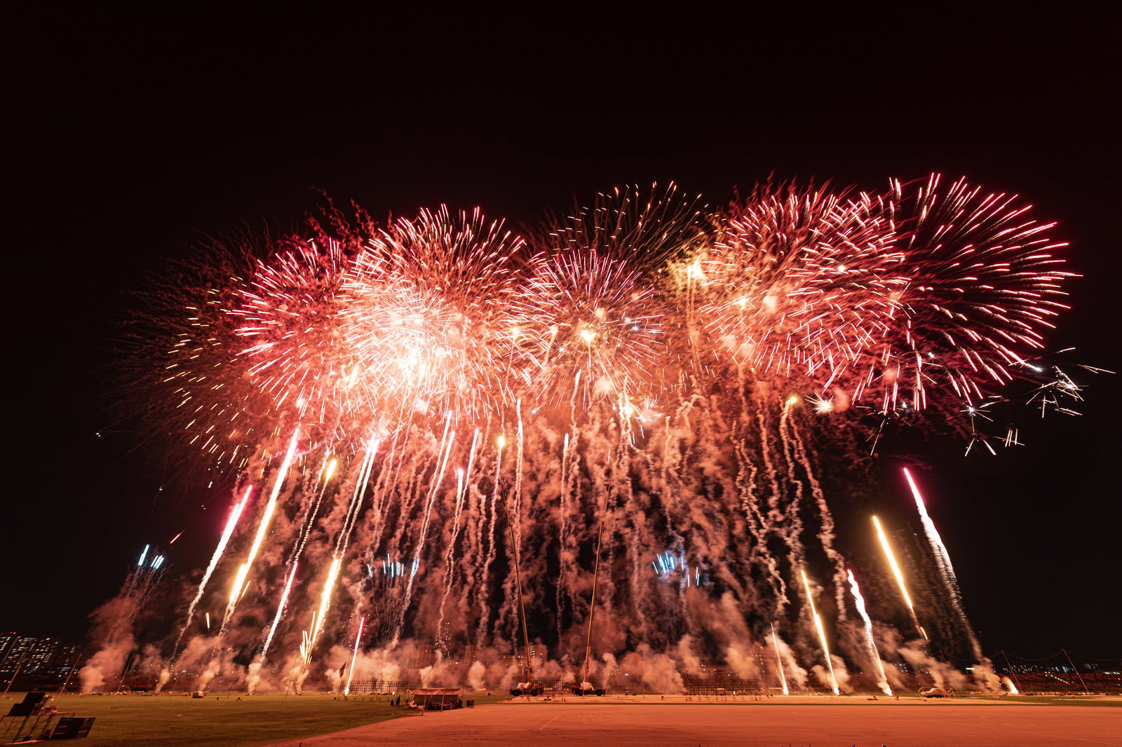 夜空に赤やオレンジ色の花火が次々と打ち上がるスターマイン