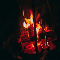 薪を入れて炎が燃え上がる焚き火の炎と薪が燃える様子の写真