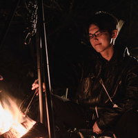 焚き火を前にソロキャンする眼鏡をかけた男性の写真