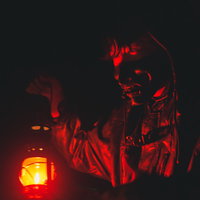 闇の中、赤いランタンを持って徘徊する野盗の男性の写真